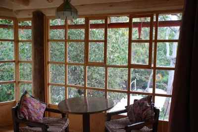 a room with a table and chairs and large windows at IORANA HOTEL Urubamba in Urubamba