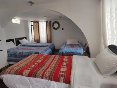 three beds in a room with an arch at Hostal Killaly Inn Cusco in Cusco