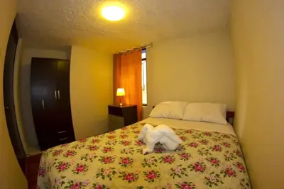 a white dog standing on a bed in a bedroom at Mi Pueblito Lodge in Huancayo