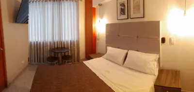 a bedroom with a bed with white sheets and a window at LUMA SUITE in Lima