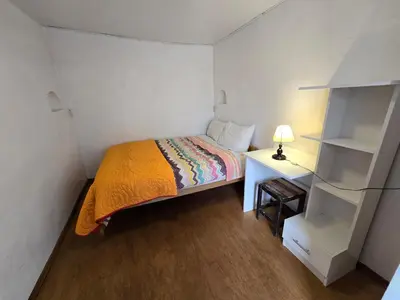 a small bedroom with a bed and a desk with a lamp at Barrio Inka B&B in Cusco