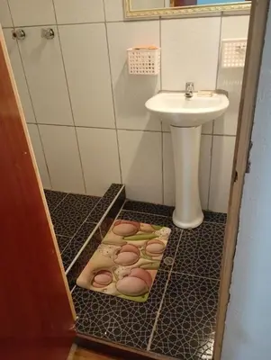 a bathroom with a sink and a toilet and a floor with a drain at Barrio Inka B&B in Cusco