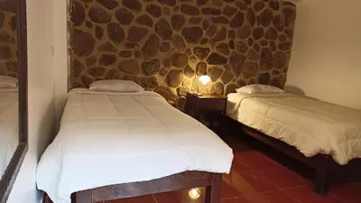 two beds in a room with a stone wall at Los Apus Ollantaytambo in Ollantaytambo