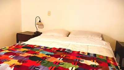 a bedroom with a bed with a colorful quilt on it at Los Apus Ollantaytambo in Ollantaytambo