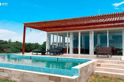 a swimming pool in front of a house at HOP BUZIOS exclusiva oasis y playa en Chincha in Chincha Baja