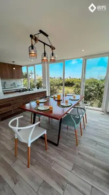 a dining room with a table and chairs and windows at HOP BUZIOS exclusiva oasis y playa en Chincha in Chincha Baja