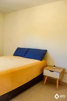 a bedroom with a bed with a blue pillow and a table at HOP LAGO & MAR exclusiva en playa de chincha in Chincha Baja