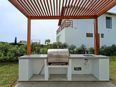 a barbecue grill sitting under a wooden pergola at HOP ODAIBA exclusiva laguna y playa en Chincha in Chincha Baja