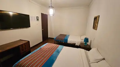a hotel room with two beds and a flat screen tv at Natural B&B Guest House in Cusco