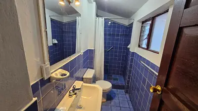 a blue tiled bathroom with a sink and a toilet at Natural B&B Guest House in Cusco