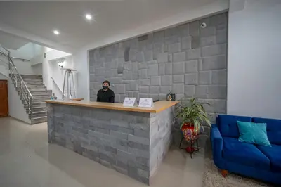 a woman standing at a counter in a lobby with a blue couch at Ayni Cusco Hotel in Cusco