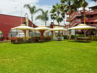 a lawn with tables and umbrellas in front of a building at Hotel Los Arcos de Imperial in San Vicente de Cañete