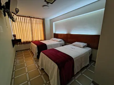 a hotel room with two beds and a window at Hotel Los Arcos de Imperial in San Vicente de Cañete
