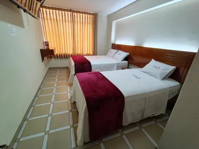 two beds in a small room with a window at Hotel Los Arcos de Imperial in San Vicente de Cañete