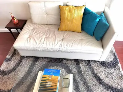 a white couch with pillows and a book on a table at Espacio Luxury Apartments Malecón 2 in Lima