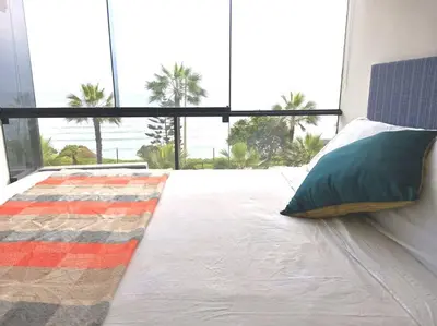 a bedroom with a bed and a large window with palm trees at Espacio Luxury Apartments Malecón 2 in Lima