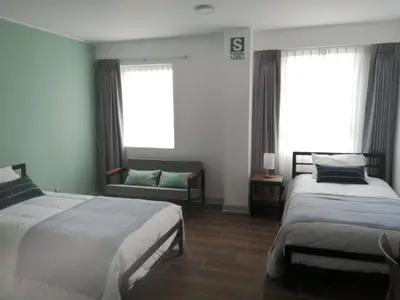 a bedroom with two beds and a couch and windows at NEREO rooms in Lima
