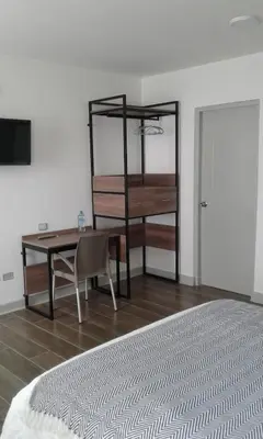 a bedroom with a desk and a table and a bed at NEREO rooms in Lima