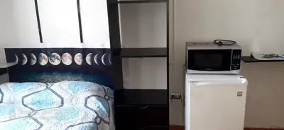 a room with a bed and a microwave on a refrigerator at Acojedor in Lima