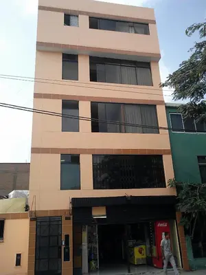 a tall building with a man walking in front of it at Hostal Jovita in Lima