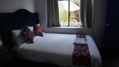 a bedroom with a bed with a window and pillows at PARDOS HOUSE INN in Cusco