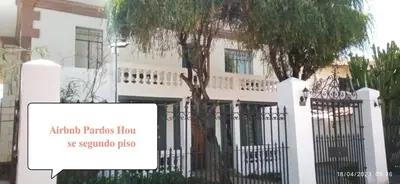 a white house with a tree in front of a fence at PARDOS HOUSE INN in Cusco