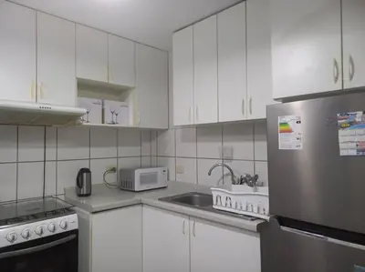 a kitchen with white cabinets and a stainless steel refrigerator at Lugar encantador frente al mar con tina o jacuzzi in Lima
