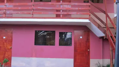 a pink house with a red door and stairs at Garden Inn 488 in Cusco