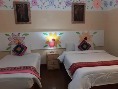 two beds in a room with flowers on the wall at Reinbo Garden in Cusco