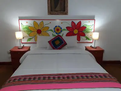 a bedroom with a white bed with flowers on the wall at Reinbo Garden in Cusco
