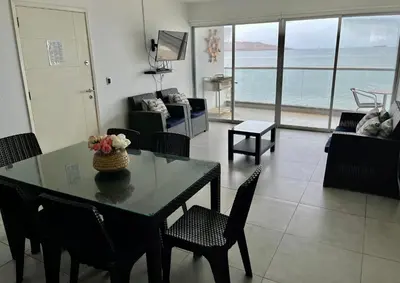 a living room with a table and chairs with a view of the ocean at 1 Fila Vista Bahía Paracas - La Velas 501 T1 in Paracas