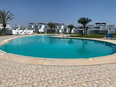 a large blue swimming pool with palm trees and buildings at 1 Fila Vista Bahía Paracas - La Velas 501 T1 in Paracas