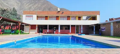 a house with a swimming pool in front of a building at Amachito's Casa Recreacional in Lima