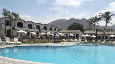 a resort with a large pool and chairs and mountains at VPX Hoteles Cieneguilla in Cieneguilla