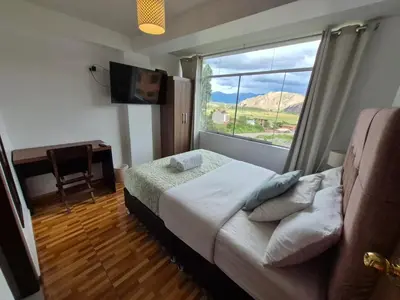 a bedroom with a bed and a window and a desk at Casa Yanahuara Valle Sagrado - Urubamba in Urubamba