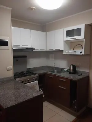 a kitchen with white cabinets and a sink and a stove at departamento de 1 dormitorio in Lima