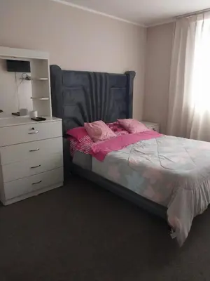 a bedroom with a bed with pink sheets and a dresser at departamento de 1 dormitorio in Lima