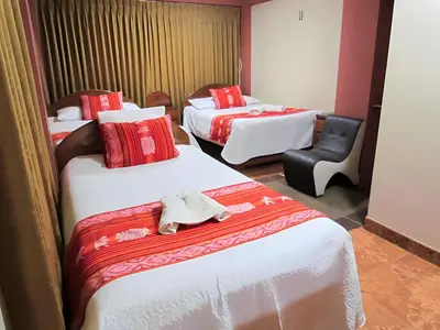 a hotel room with two beds and a chair at Hotel Colquewasi in Cusco