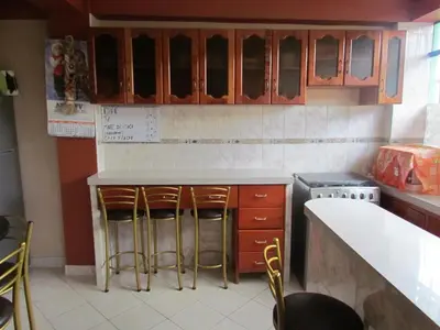 a kitchen with wooden cabinets and bar stools at Hotel Colquewasi in Cusco