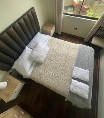 a bedroom with a bed with a white dog laying on it at Departamento completo Surquillo/Miraflores in Lima