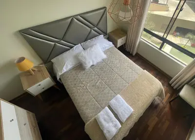 a bedroom with a bed with a gray head board at Departamento completo Surquillo/Miraflores in Lima