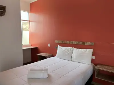 a bedroom with a white bed with an orange wall at La Estancia Hotel Ica in Ica