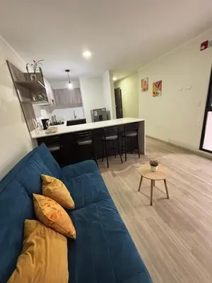 a living room with a blue couch and a kitchen at Apartamento acogedor en Barranco - cerca a Miraflores in Lima