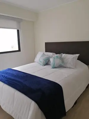 a large white bed with blue sheets and pillows at Apartamento acogedor en Barranco - cerca a Miraflores in Lima