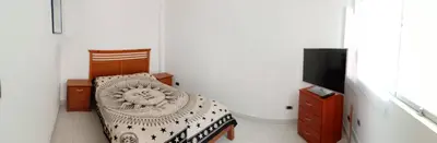 a room with a bed and a tv and a chair at Departamentos Cerro Azul P1 in Cerro Azul