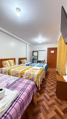 a room with two beds and a flat screen tv at El Sol de Nazca in Nazca