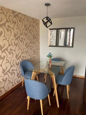 a dining room with a glass table and blue chairs at Departamento completo en Miraflores Surquillo in Lima