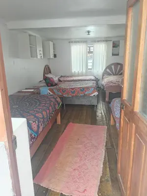 a room with three beds and a door with a rug at Hostel mágico San Blas in Cusco