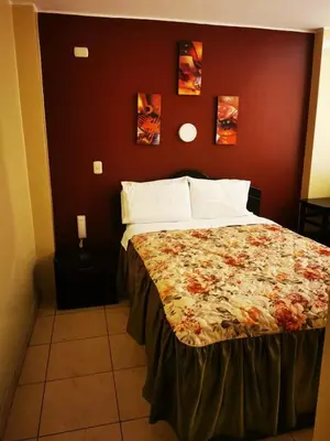 a bedroom with a bed with a floral bedspread at Los Sauces in Huacho