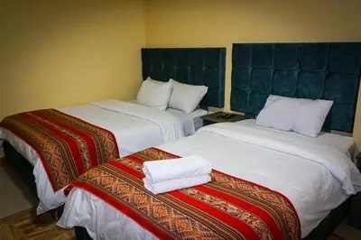 two beds in a hotel room with towels on them at Cusco Hawka Pacha hostal in Cusco